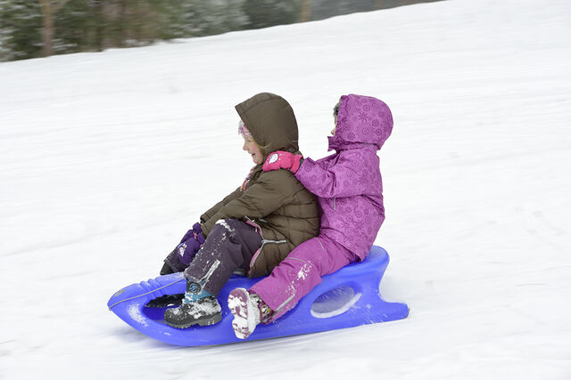 Two children sledding in snow
